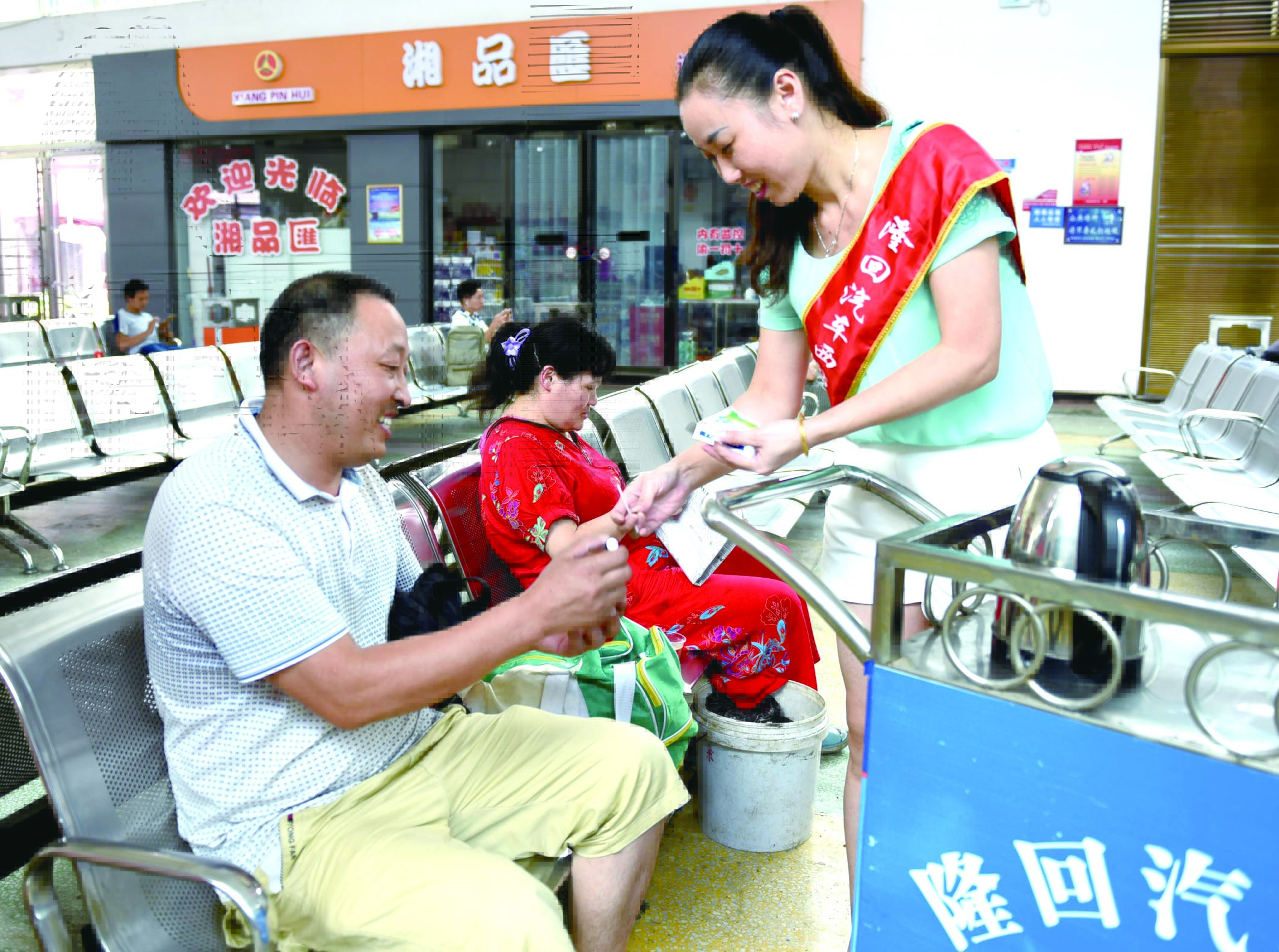 隆回分公司汽車西站工作人員正在為旅客免費(fèi)贈送藿香正氣水。